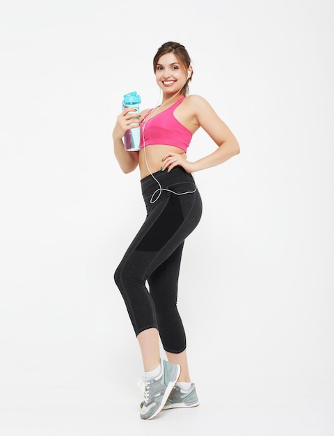 Sport people and fitness concept young woman wearing sport wear holding a bottle with water over white background