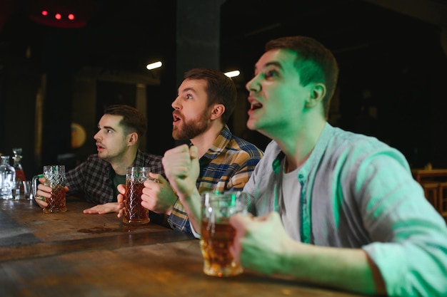 Sport people leisure friendship entertainment concept happy male football fans or good yuong friends drinking beer celebrating victory at bar or pub Human positive emotions concept