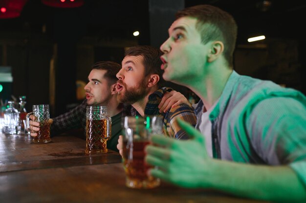 Photo sport people leisure friendship entertainment concept happy male football fans or good yuong friends drinking beer celebrating victory at bar or pub human positive emotions concept