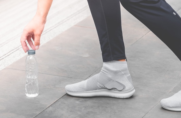 Sport runner is picking drinking water from the ground