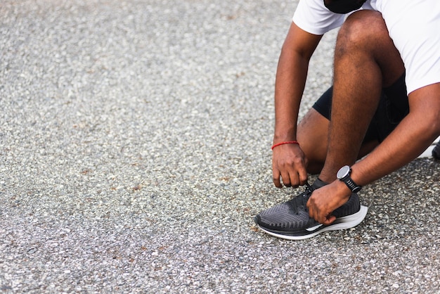 Sport runner zwarte man dragen horloge zitten hij probeert schoenveter loopschoenen