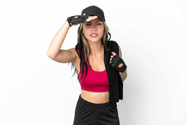 Sport Russian girl with hat and towel isolated on white background looking far away with hand to look something