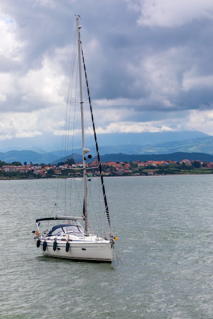 Sport sail boat moored in bay with calm sea and threatening sky