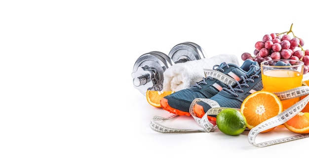 Scarpe sportive manubri frutta fresca misura nastro e succo multivitaminico isolati su sfondo bianco. sport sano e concetto di dieta.