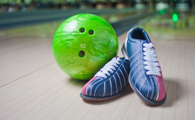 Scarpe sportive e palla verde sul pavimento nel randello di bowling