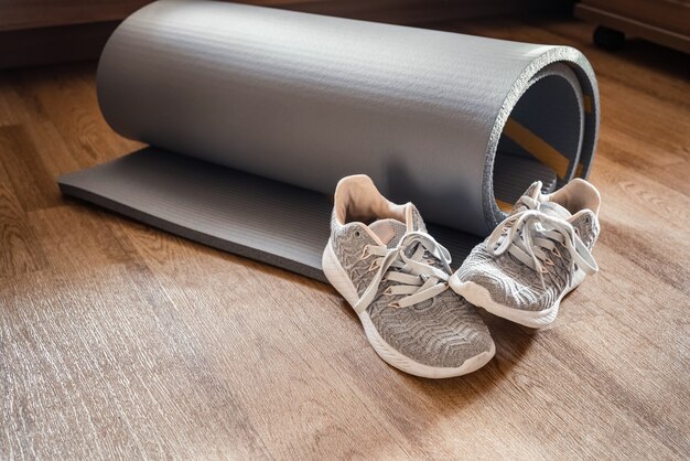 Photo sport shoes stands next to twisted yoga mat