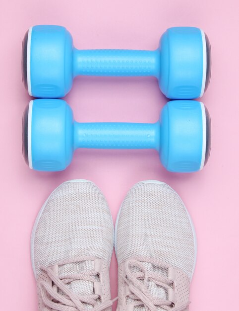 Sport shoes with dumbbells on pink