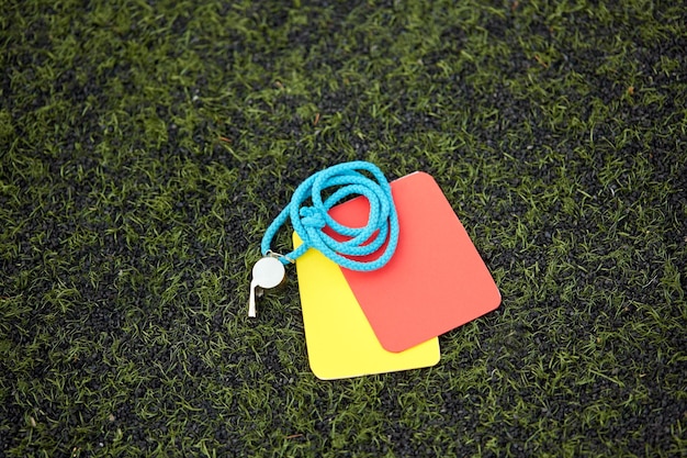 sport, soccer and game - referee whistle and caution cards on football field