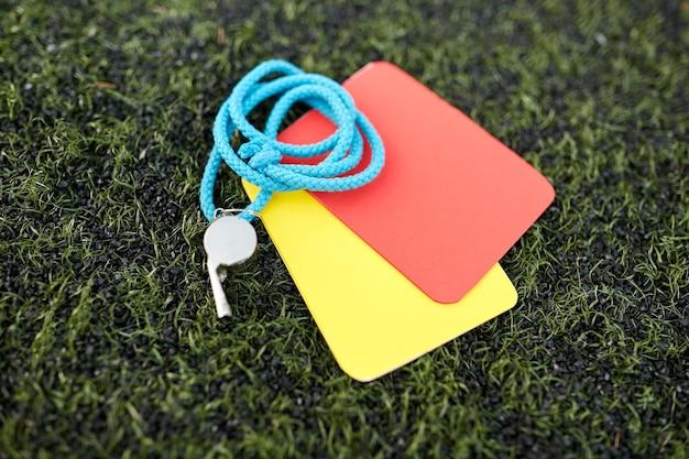 Photo sport, soccer and game - whistle and caution cards on football field