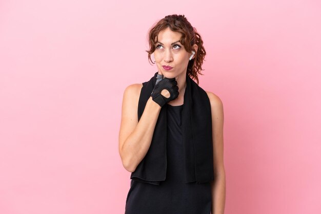 Sport sport woman with towel isolated on pink background having doubts and with confuse face expression