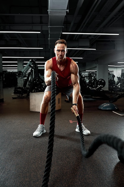 Sport Sterke man die traint met gevechtstouwen in de sportschool met atleet die gevechtstouwtraining doet in de sportschool Dramatische sportachtergrond