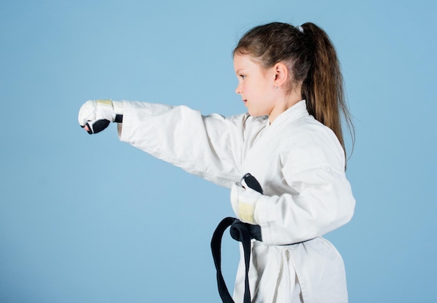 Sport success in single combat practicing Kung Fu happy childhood little girl in gi sportswear small girl in martial arts uniform knockout energy and activity for kids Free your mind