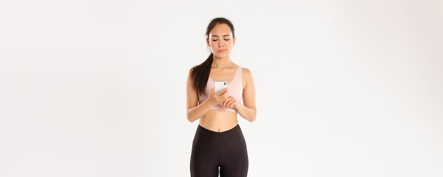 Tecnologia sportiva e concetto di stile di vita attivo ragazza fitness guardando lo schermo del suo smartphone con ups