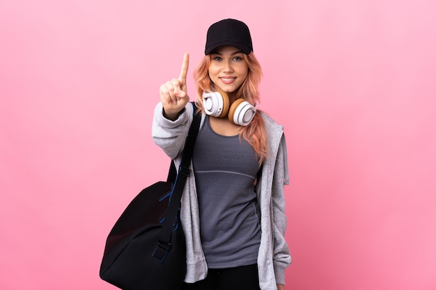 sport teenager girl with sport bag over isolated showing and lifting a finger