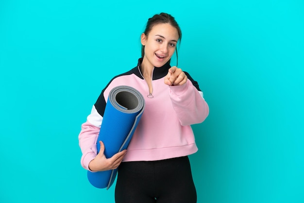 Sport Ukrainian woman going to yoga classes while holding a mat surprised and pointing front