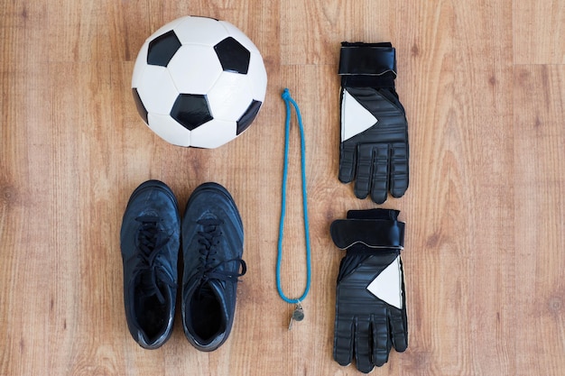 sport, voetbal en sportartikelen concept - close-up van voetbal, laarzen, fluitje en handschoenen op houten achtergrond