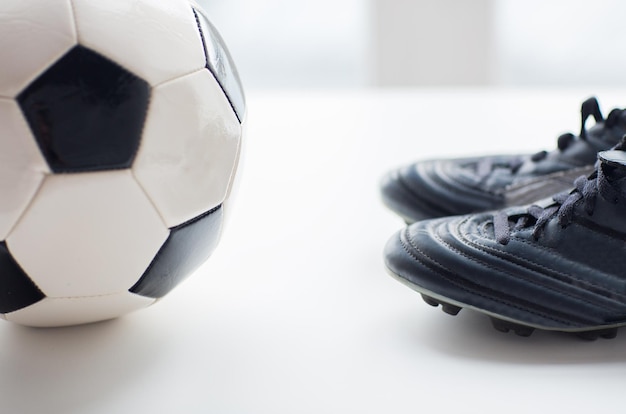 sport, voetbal, voetbal en sportartikelen concept - close-up van bal en laarzen op tafel