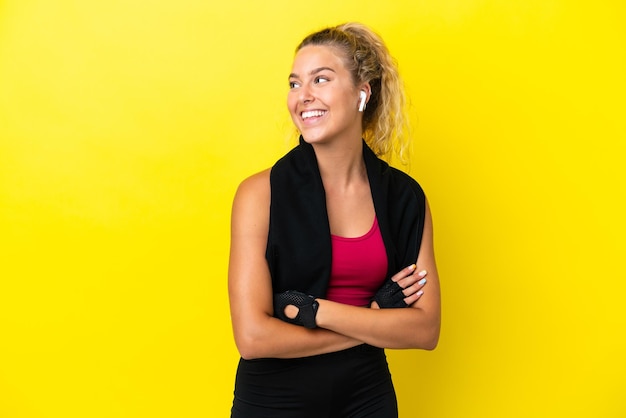 Sport vrouw met handdoek geïsoleerd op gele achtergrond op zoek naar kant