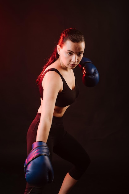 Photo sport woman boxer wearing blue boxing gloves on dark background