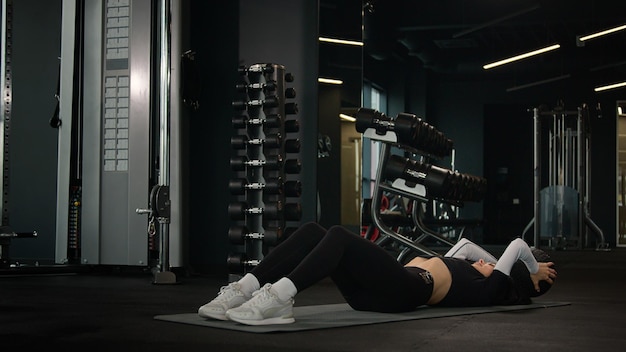 Sport woman caucasian fit girl sportswoman athlete trainer exercising on fitness mat in dark gym