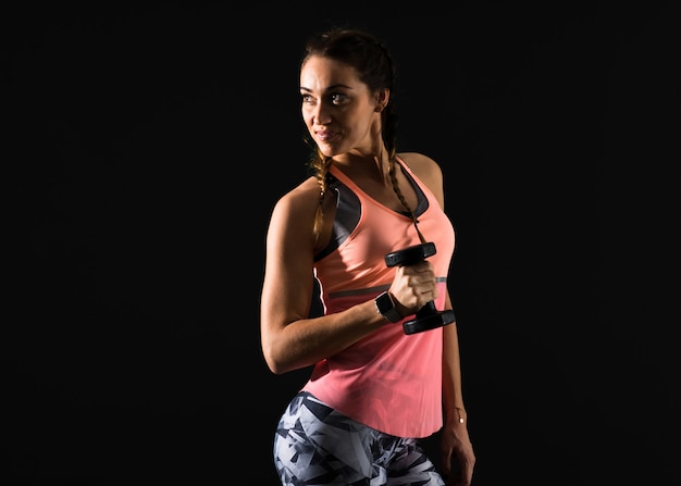 Sport woman on dark background making weightlifting