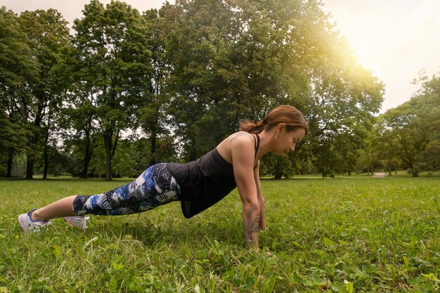 Sport woman doing fitness push up in park