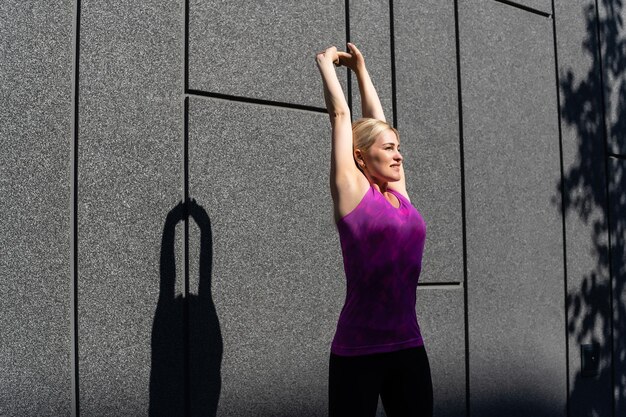 Спортивная женщина делает упражнения на растяжку во время кросс-тренировки на открытом воздухе