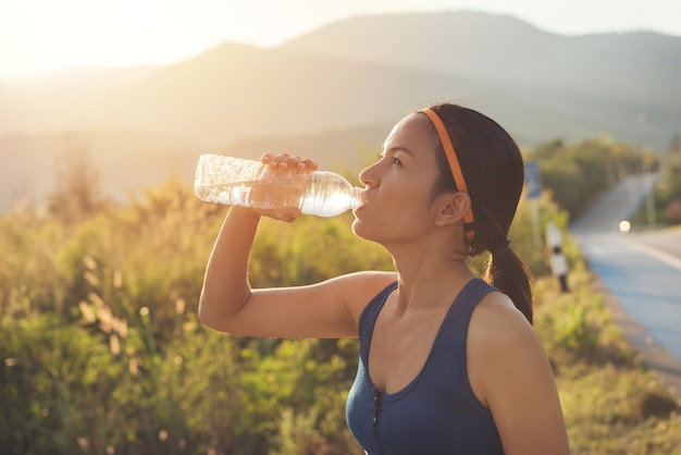 朝のジョギング中にスポーツの女性の飲料水