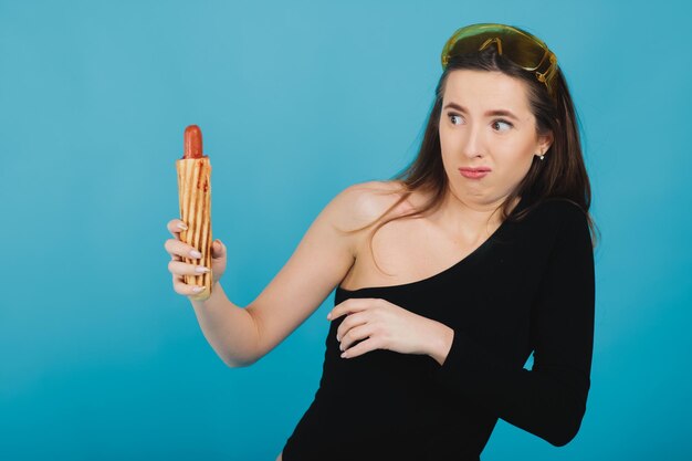 Foto donna sportiva nel mangiare hot dog su sfondo blu