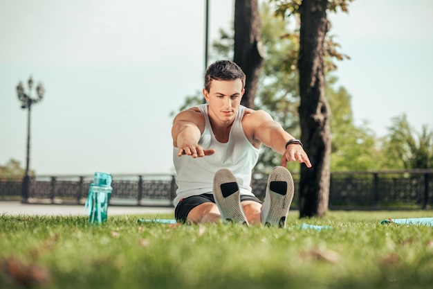 Sport woman exercising on mat in the park at daytime