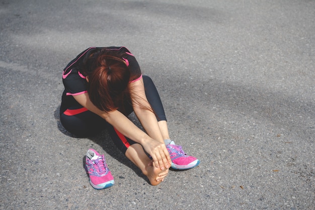 Sport woman feeling pain in her foot after running. Injury from workout concept