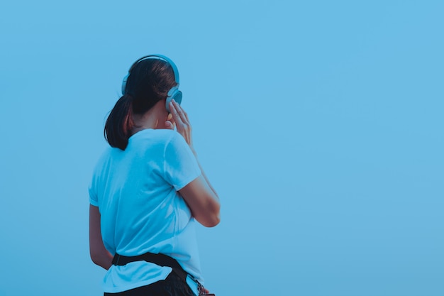 Sport woman listening to music with earphones in blue background.