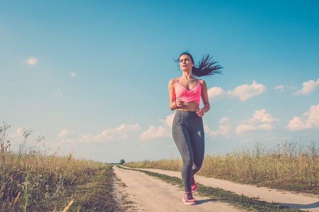 The sport woman running in the field path