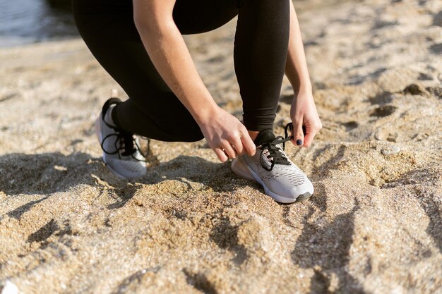 Sport woman tying shoelaces on the beach