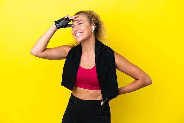 Sport woman with towel isolated on yellow background has realized something and intending the solution