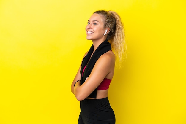 Sport woman with towel isolated on yellow background in lateral position