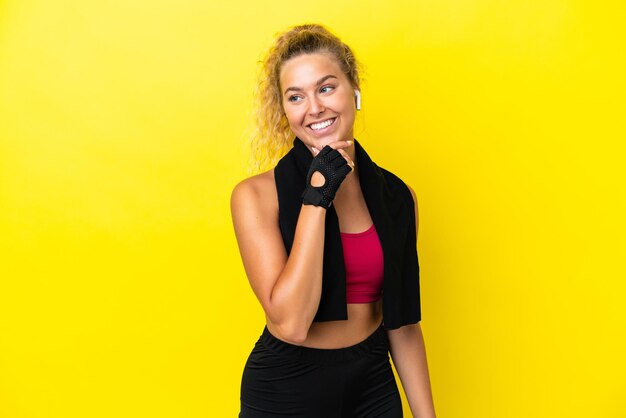 Sport woman with towel isolated on yellow background looking to the side