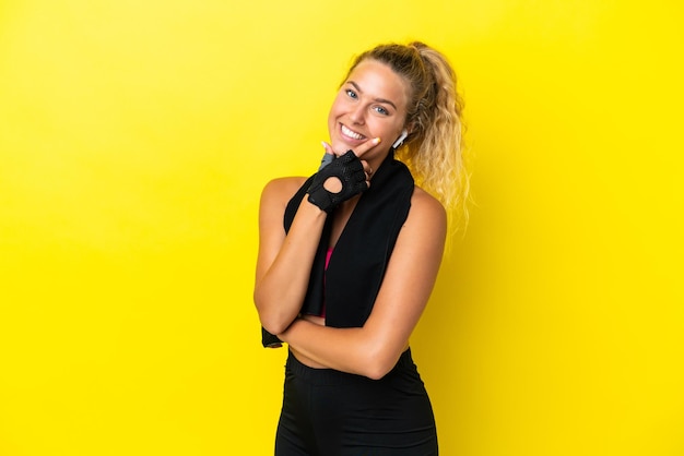 Sport woman with towel isolated on yellow background smiling