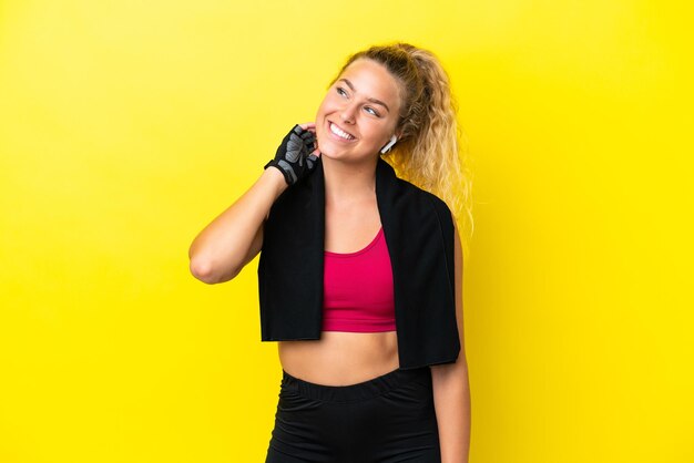 Sport woman with towel isolated on yellow background thinking an idea