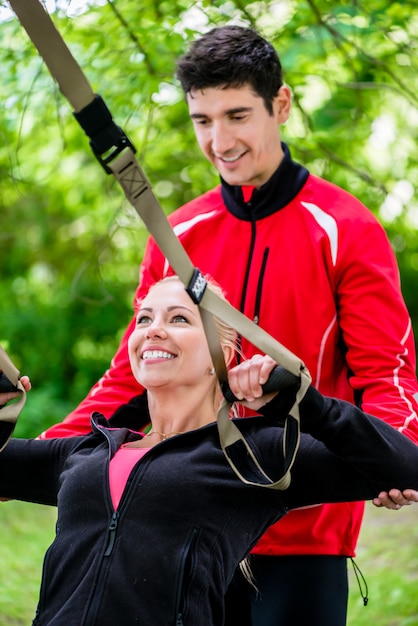 Sport woman with trainer at sling training