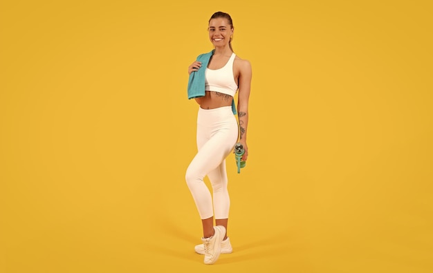 Sport woman with water bottle on yellow background