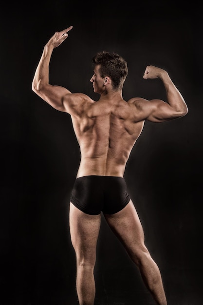 Sport and workout. Athletic bodybuilder pose in pants. Man with muscular body. Gladiator or atlant. Adam with bare back.