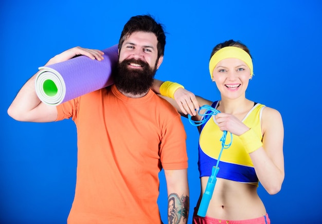 Sport workout equipment happy woman and bearded man workout in\
gym sporty couple workout with fitness mat and skipping rope strong\
muscles and body athletic success everyday workout together