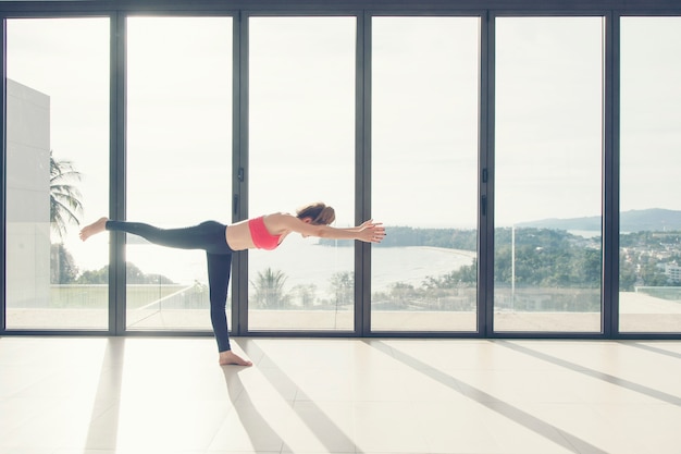 Sport Young woman practicing yoga indoor class sea view