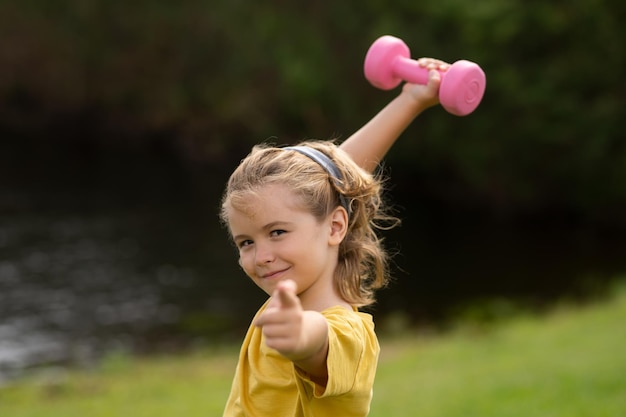 Sportactiviteiten op uw gemak met kinderen Blonde jongen met halters Sportoefeningen voor kinderen Grappig kind dat de halters optilt