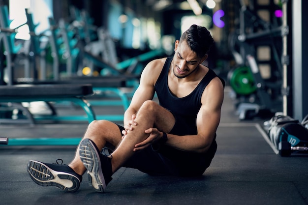 Sportblessure arabische mannelijke atleet die knietrauma lijdt tijdens het trainen in de sportschool