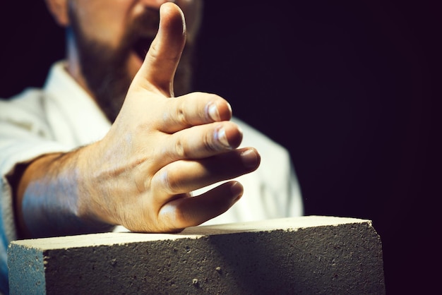 Sportconcept gedeeltelijke weergave van een karate man in kimono bebaarde man die de betonnen plaat breekt met