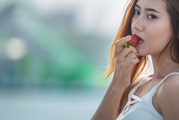 Sporten Aziatische gelukkige vrouw die aardbei eet.