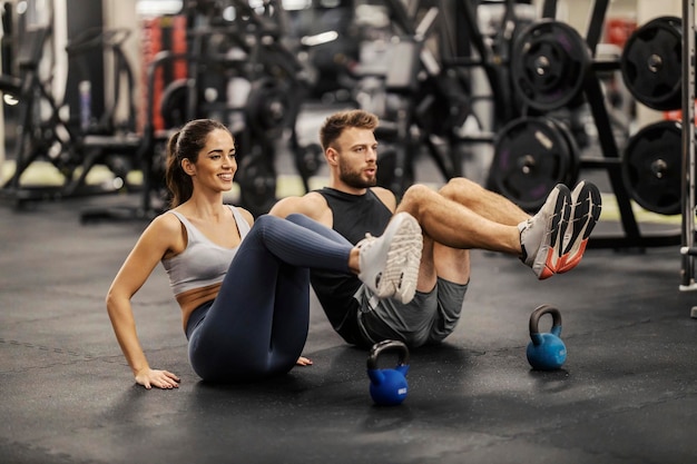 Foto sporters die abdominale oefeningen doen en op de sportschoolvloer zitten