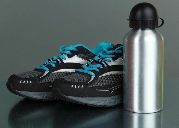 Sportfles en sneakers op grijze achtergrond
